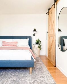 a bed sitting next to a wooden door in a bedroom on top of a hard wood floor