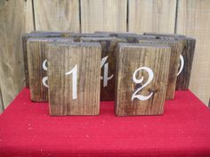 three wooden blocks with numbers on them sitting on a red cloth covered bench next to wood planks