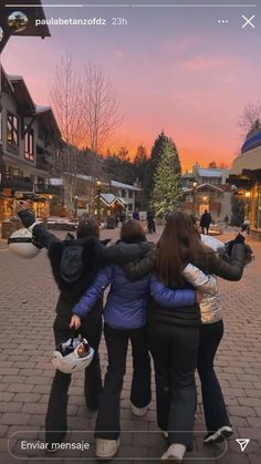 three women hugging each other in the middle of a city street at sunset or dawn