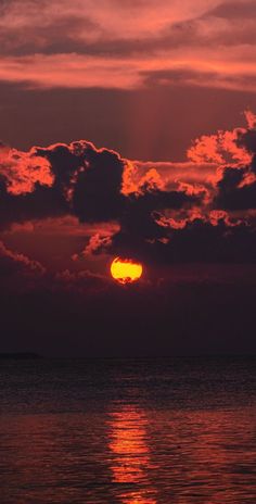 the sun is setting over the ocean with clouds in the sky and water below it