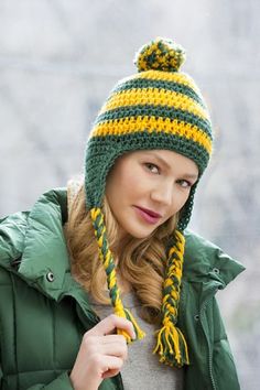 a woman wearing a green and yellow knitted hat with pom - pom