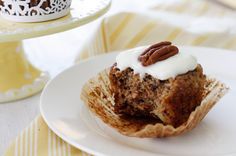 a cupcake with frosting and pecans sits on a plate