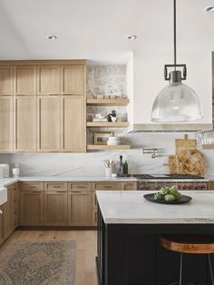 a kitchen with wooden cabinets and white marble counter tops, an island in the middle