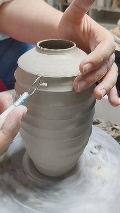 a person is making a vase out of clay