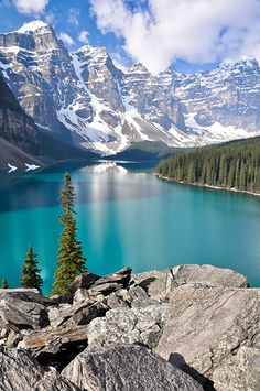 a lake surrounded by mountains and trees with blue water