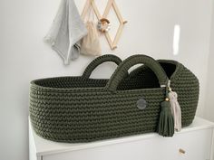 a large green basket sitting on top of a white dresser next to a stuffed animal