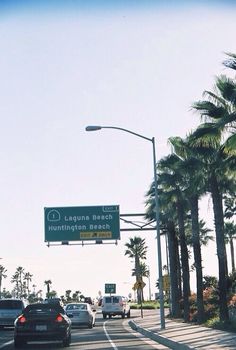 cars are driving down the street in front of palm trees and a sign that says la joque beach municipal beach