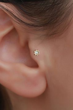 a woman's ear is shown with a small diamond in the shape of a flower