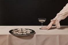 a painting of a woman sitting at a table next to a plate of oysters