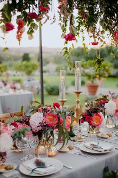 a table set with flowers and candles for an outdoor wedding reception in the evening hours