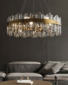 a modern chandelier hanging from the ceiling in a living room with grey walls