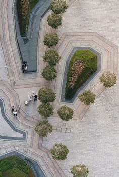 an aerial view of people walking around in a courtyard with stone walkways and trees