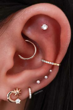 a woman with three different ear piercings on her left ear and one has a star, moon, and crescent