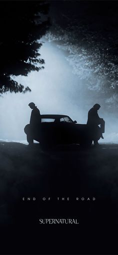 two men standing next to a car in the dark with fog coming from behind it