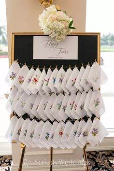 a table topped with lots of white napkins next to a black and gold sign