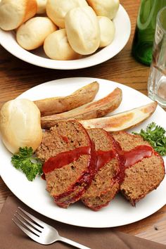 meatloaf with ketchup and potatoes on two plates next to a glass of water