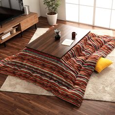 a living room with a couch, coffee table and rug on the floor in front of a flat screen tv