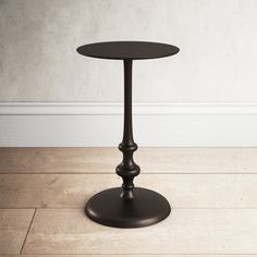 a small black table on the floor in front of a white wall and wooden floors