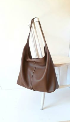 "This hand bag is crafted from textured soft leather in chocolate brown . It's the ideal size for taking you from desk to dinner, and can be worn over the shoulder for hands-free. -One shoulder straps. - Pleated top with magnetic fastening. - You can choose from 6 leather colors. - Cotton lining with zip close compartment for securing your necessities, you can choose from 7 different linings. Free delivery is economic delivery. We use Latvian post and delivery can take 1-3 weeks in the EU, 3-4 w Cheap Brown Bags, Slouchy Brown Leather Bag, Brown Slouchy Bag, Black Leather Shoulder Bag For School, Brown Leather Hobo Bag, Slouchy Shoulder Bag, Tod Bag, Slouchy Leather Tote, Leather School Bag