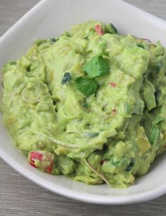 a white bowl filled with guacamole on top of a table