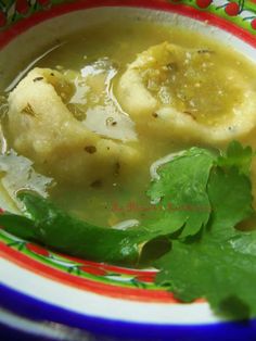 a bowl filled with soup and garnished with cilantro leaves on the side