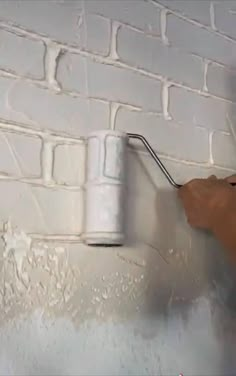 a person painting a brick wall with white paint