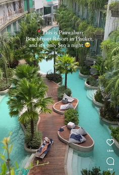 two people are sitting on benches in the middle of an outdoor swimming pool that is surrounded by palm trees