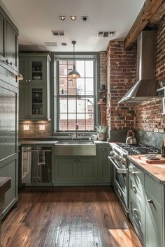 a kitchen with green cabinets and wooden floors, along with a brick wall in the background