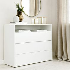 a white dresser sitting in front of a mirror and a vase on top of it