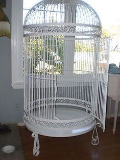 a white bird cage sitting on top of a wooden floor