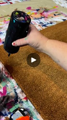 a person holding a black cup on top of a rug