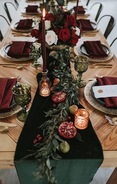 the table is set with candles, plates and red napkins on top of it