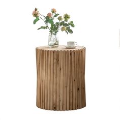 a vase with flowers on top of a wooden table next to a cup and saucer