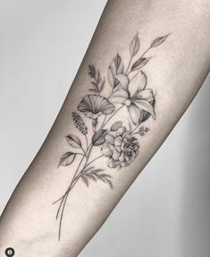 a woman's arm with flowers and leaves on it