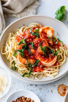 pasta with shrimp and tomato sauce in a white bowl next to other dishes on the table