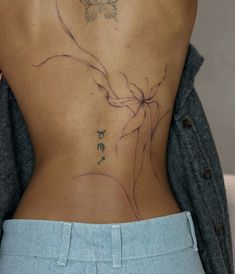 the back of a woman's body with tattoos on her lower and lower back