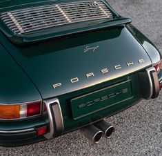 the back end of a green porsche parked on asphalt with its exhaust pipe out and it's hood up