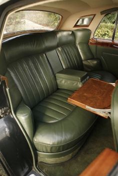 the interior of an old car with green leather seats and wood table in center console