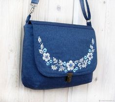 a blue purse with flowers on it hanging from a wooden wall next to a pair of scissors