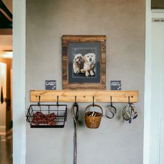 two dogs are hanging on the wall above a coat rack with hooks and baskets underneath