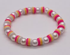 a bracelet with white, yellow and pink beads is shown against a white background in this image