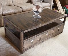 a coffee table with drawers underneath it in front of a couch and window sill