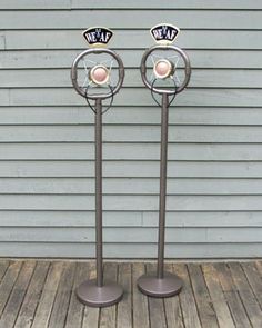 two metal poles with balls on them sitting in front of a wall and wooden floor