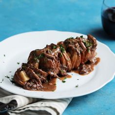 a white plate topped with meat covered in gravy