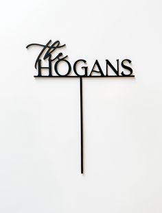 a sign that says hogans on top of a wooden stick in front of a white wall