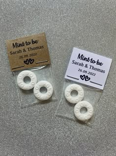 two small white rings sitting on top of a table next to a label that says minttobe and thomas