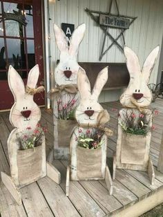 four white rabbits are sitting in burlocks on the porch with flowers and grass