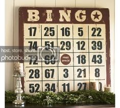 a wooden sign with numbers on it and candles in front of the board that says bingo