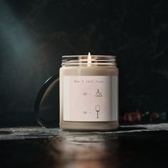 a lit candle sitting on top of a wooden table next to a black mug with the words, how is this time?