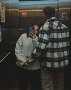 a man and woman taking a selfie in an elevator